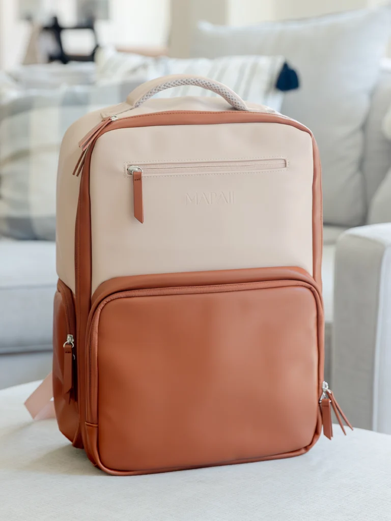 Tan and brown Mapaii backpack placed on a soft beige surface in a cozy living room setting