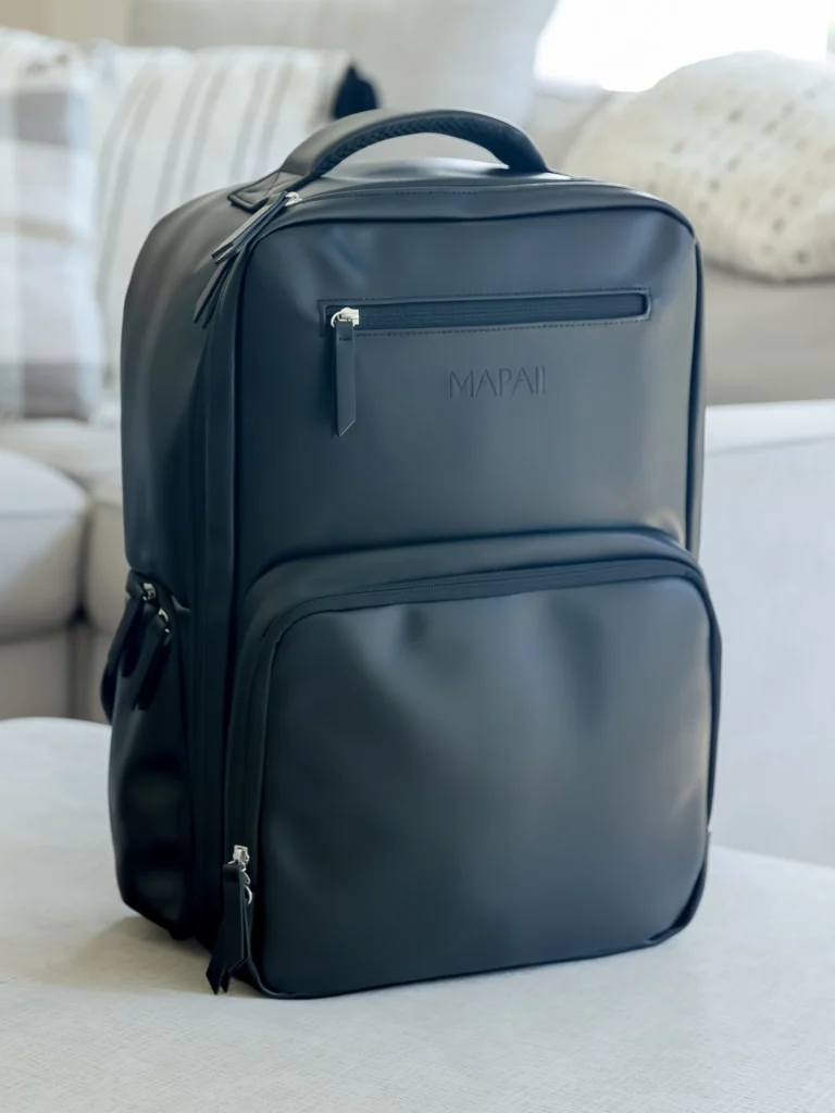 Black Mapaii diaper backpack displayed on a modern white couch in a bright living room
