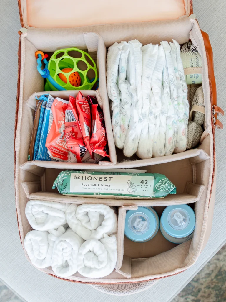 Open Mapaii diaper backpack neatly packed with baby essentials including diapers, snacks, bottles, toys, and wipes