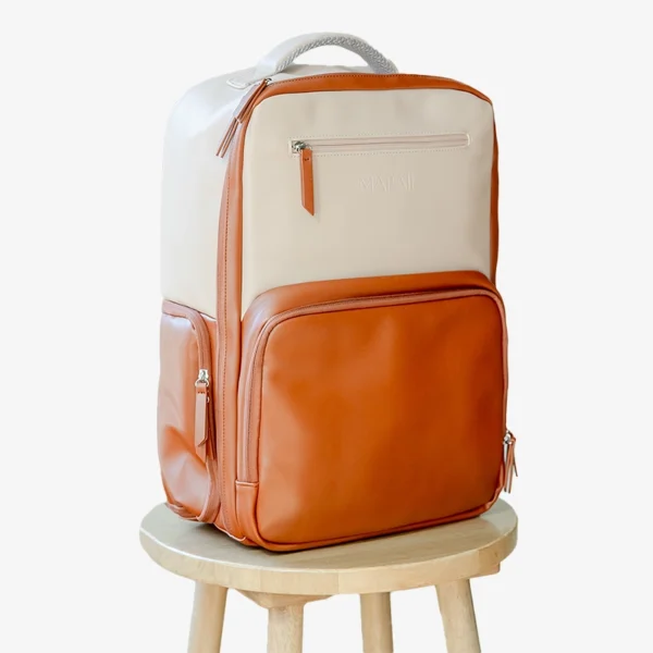 Tan and brown Mapaii backpack displayed on a wooden stool with a white background