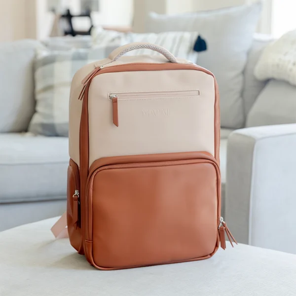 Tan and brown Mapaii backpack placed on a soft beige surface in a cozy living room setting